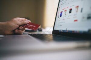 hand holding credit card by laptop before making online purchase