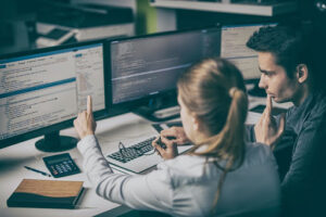 An image of two people looking at code on computer screens dealing with hosting issues.